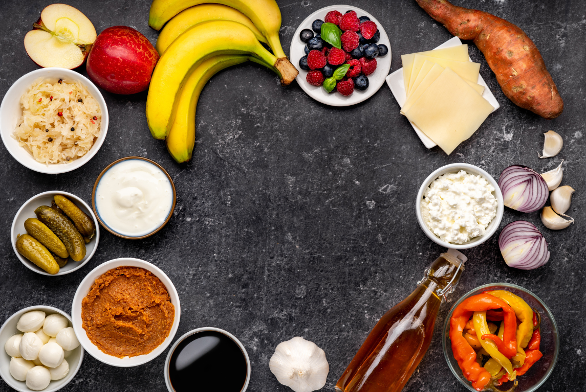 Probiotic and prebiotic foods for gut microbiota health: sauerkraut, yogurt, pickles, miso, apple cider vinegar, garlic, onion, cheese, sweet potato, bananas, apples, berries.